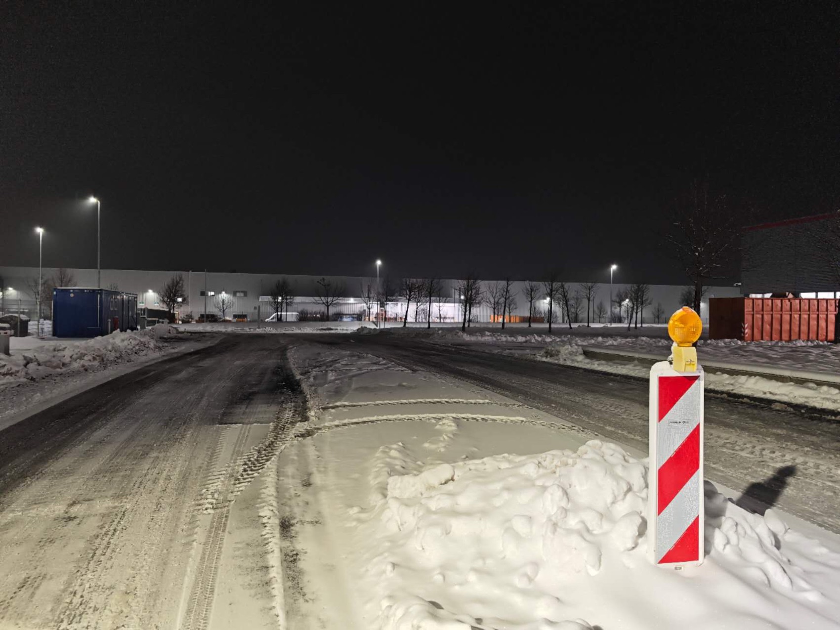 Cleared industrial access road with snow banks during night operations