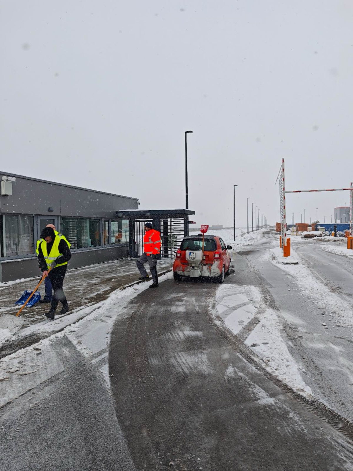 Winter service team clearing an industrial access road with a compact vehicle